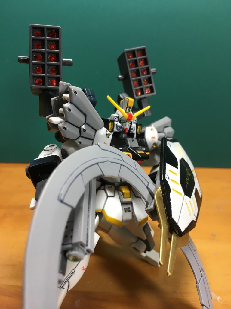 バックパック左右の装備したアームは3mm軸接続である程度換装が自由に出来ます。今回サンドロック製作に合わせてHGBC「ボールデンアームアームズ」からミサイルポッドも製作。裏がすっぽ抜けているので0.5mmプラ板でふさぎ、ウェーブの「U・バーニアフラット(角型)」やプラ板、スジ彫りでディテールを追加しました。
 その後3mmプラ棒を穴に突っ込んでアタリを取り、その長さに合わせて20本切り出しました。フタパーツを取り付けるため、ミサイルの弾頭は穴の縁と同じ位置になるように切り出すといいです。弾頭を赤く塗ってからすべて差し込み、瞬着で固定しました。
 3本のピンは他のキットに使いまわせるように考え、あえてそのままにしています。
 塗装はガンダムマーカー中心です。
塗装下地=Mr.サーフェイサー1000
白=Mr.ベースホワイト1000
赤=ガンダムマーカー ガンダムレッド
黄色=同イエロー
緑=同蛍光グリーン
黒=同ブラック
金=同ゴールド