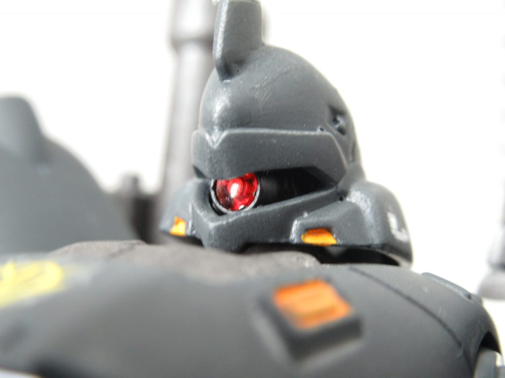 頭部モノアイのアップ写真。MSサイトレンズの赤（ビルダーズパーツ）を使用し、クリアパーツを挟めこむ際、間にアルミ箔を挟めてホイルシール使用時と同等の効果を引き出しています。肉眼で見るとあまりその効果がわかりにくいです…
モノアイが奥まっているのが原因。これはしょうがないね。