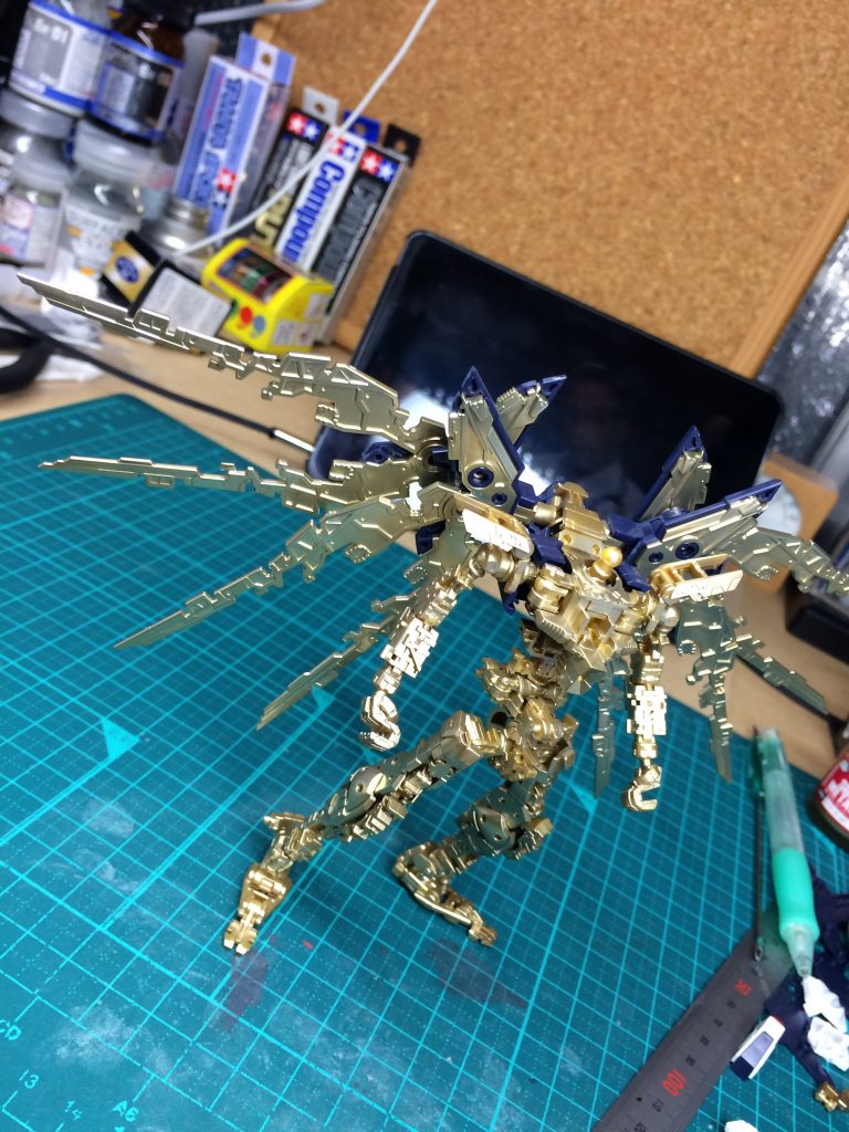 前回は部分塗装と言うことで手をつけていなかったアドヴァンスドMSジョイント。
普通に塗装すると溶剤の影響で割れるとの情報があったので、ガイアのマルチプライマーで素材を保護し、今となってはどうやって作ったのか思い出せない奇跡の金色を吹きつけて、トップコートにガイアの蛍光クリアにMrクリスタルカラーのトパーズゴールドを混ぜたものを、薄く何層も重ねてみました。
羽の部分のメッキは落としてから同色塗装です。
