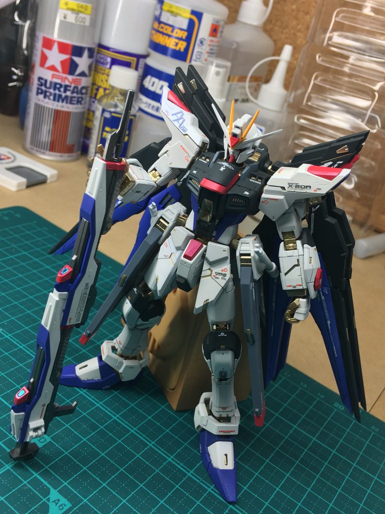 パッケージの絵を参考に、本来金色であるはずの部分や、膝のダクト周りのグレーなど、可能な限り塗り分けしました。
黒の部分、元の色は若干紺色っぽいのですが、イメージでは黒に近いものだったので、僅かにグリーンとグレーを混ぜた、限りなく黒に近いグレーにしてみました。トップコートは単純につや消しのみのマットな質感に。
装甲の白い部分はフィニッシャーズのスーパーシェルホワイト。トップコートにはつや消しにMrクリスタルカラーのサファイアブルーを薄く混ぜて光の反射角によってはうっすら青っぽく光沢のあるように処理しました。
同じく赤い部分も同様のトップコートを施し、角度によっては紫に見えるように。
私の頭の中では、この機体は戦闘中キラキラしてるようなイメージだったので、なるべくそれを反映したかったのですが・・・どうかな?