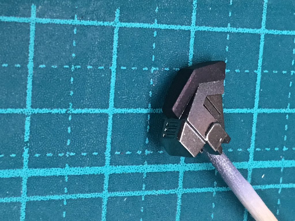 膝の部分なんですが、無駄に塗りわけました。
構造を良く見ると廃熱用のダクトがあり、その部分は膝を曲げないと露出しないようになっています。
なのでダクト部分と膝を伸ばした状態のときに隠れる部分をスターブライトアイアンにて塗装。
どうなることかと思いましたが組み上げて見るとこれが意外と良いアクセントになってくれました。
ちなみに黒の部分はトップコートのつや消しにMrクリスタルカラーのルビーレッドを混ぜて、少し赤くキラキラ光るようにしました。