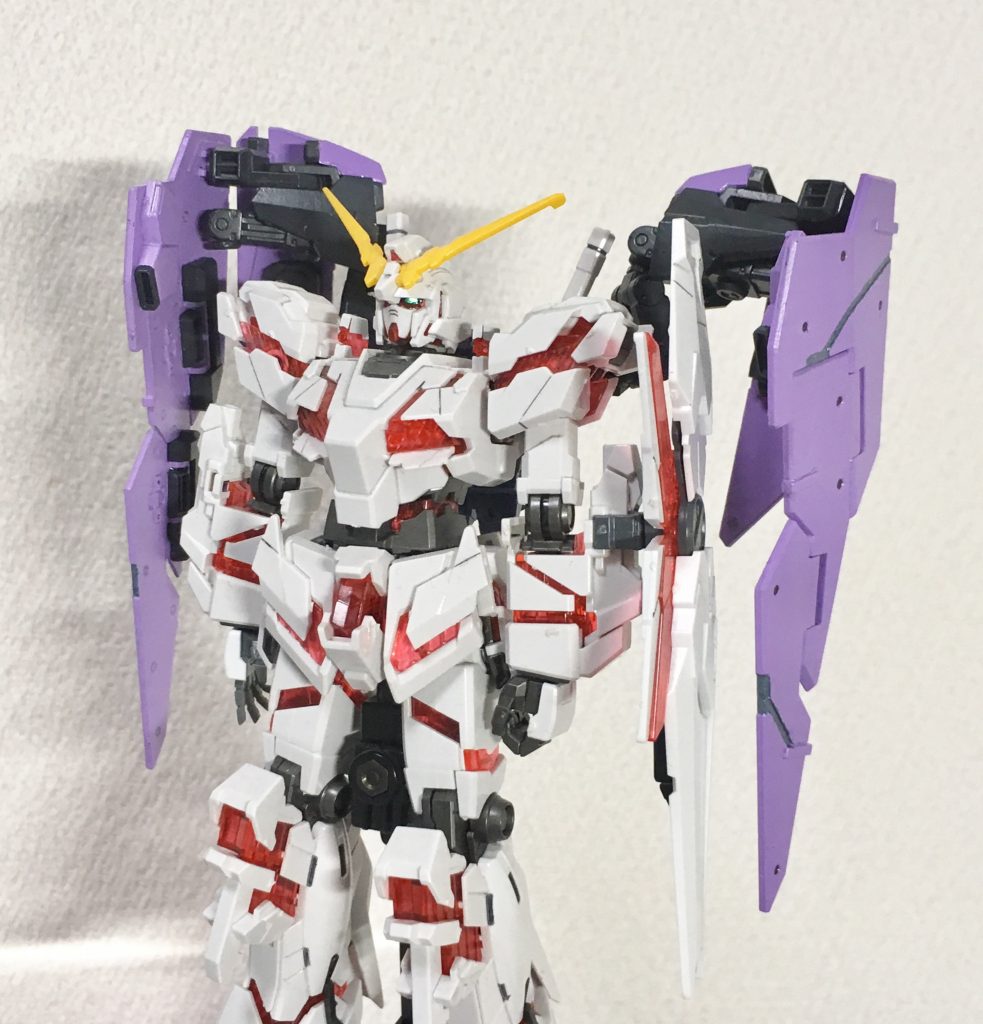 アームドアーマーという設定上、他のユニコーンにも装着出来る仕様にする為に、フェネクスの2枚のシールド保持フレームをそのまま使ってます。機体色の選定はかなり悩んだ部分で、他のユニコーンシリーズ含め主要な機体に使われてない配色であることと、ミネバorオードリーがイメージ出来る配色でもあること。ミネバ・ザビとして受領する事から正装服の緑ではクシャトリヤに被るし、赤のマントはフロンタルに被る。オードリーの白い服だと1号機に被るという事で、最終的に外陰の薄紫色に決定しました。薄紫色だからアンジェロカラーではないはず。サイコフレームの色も悩んだ末にシルバー系にしました。