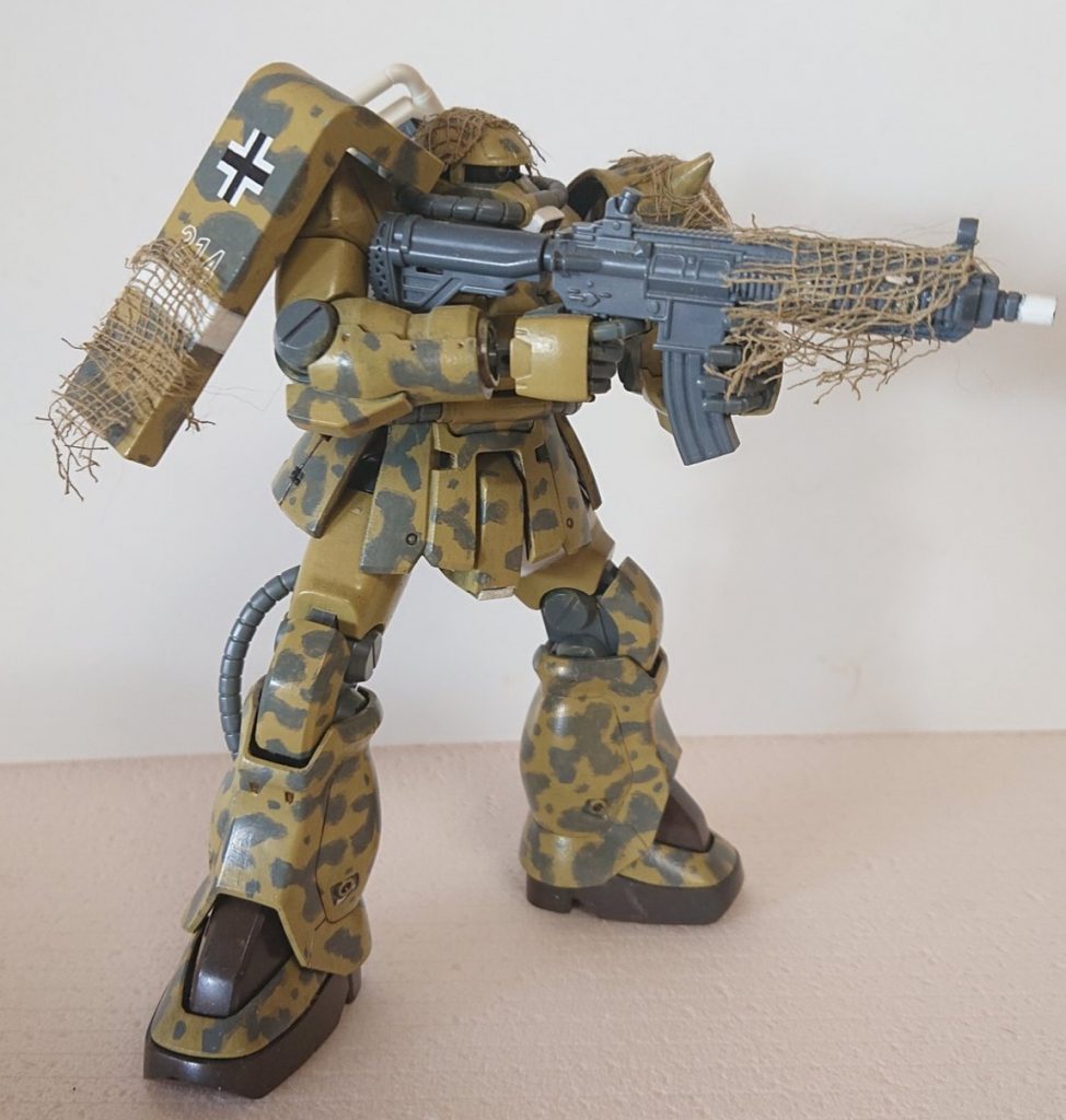 シールドには、タミヤのデカール。銃はコトブキヤのHK416風ライフルをチョイス。ほぐしたガーゼを着色したカモフラージュネット、接着は木工用ボンドで。