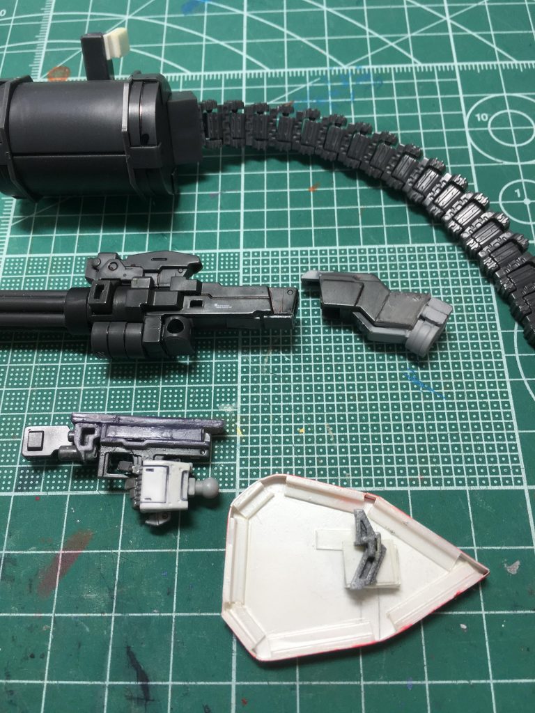 　ガトリングガンはシステムウェポン005のジャイアントガトリングガンを流用。持ち手部分は接着されたパーツに閉じ込められていたので、無理矢理分解。ビルダーズパーツHDの「MSハンド01」の左銃持ち手を使用。グリップと掌を1.5mmシンチュウ線で接続し、完全固定。

　後方に装着するストックパーツを加工し、プラ板で接続部を作りました。タンクはコトブキヤの「M.S.G ベルトリンク」。当初はウェーブの「G・タンク」とプラ板の組み合わせで自作するしかないと思っていましたが、ちょうどよく発売されたので、「これは俺のために出してくれたんだな」と勝手に思いましたｗ