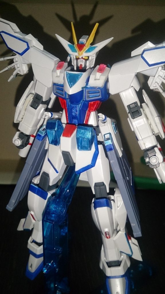 頭部アンテナにHGストフリの赤パーツをつけ、アンテナにクリアパーツを追加。
フロントアーマーにはAGE-FXのフロントを追加。
胴体のバルカン部は削り、ユニバースブースターのパーツを追加(これと上の写真は、塗装変更前です)。
これは、特殊システムを発動させた際、過剰エネルギーを光の翼として放出させるため─────という設定です。
自分の脳内設定。これもガンプラを楽しむ一つの方法ですね。