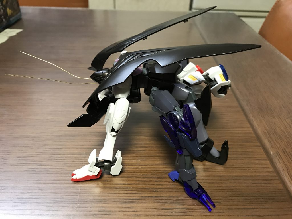 これらのポイントを押さえる為、ガンダム・ジ・エンドの頭部を“G”の頭、ゲテモノ感満載の胴体を“G”の胴、バルバトス第四形態の胴体を“G”の腹に見立てています(^^)
胸から生える前脚はバルバトス第四形態の脚部と肩パーツを利用し、真ん中の脚にはトランジェントガンダムグレイシャーの脚、後脚にはジ・エンドの脚を利用しています(o^^o)
ジ・エンドのクロークを羽に見立て、真鍮線で触覚を作り、昆虫らしいシルエットにしています( ̄▽ ̄)