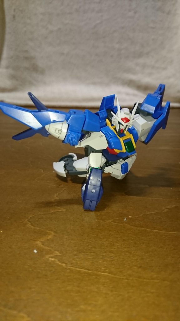 「まだ・・・まだだ!」
リクは諦めなかった。
例え絶望的なまでに実力差があろうと、例え機体のダメージが深刻だろうと、諦める理由にはならない。
サラを助ける。サラが何者でも関係ない。これからも共に、仲間たちと共に笑い合う為にも、リクはここで諦める訳にはいかないのだ。
「そうか・・・なら君に敬意を証してこの技で終わらせよう!」
そう宣言するとキョウヤは全てのファンネルのエネルギーを集約し、それを天高く打ち上げる。
『EXカリバー』
言わずも知れたクジョウ・キョウヤの必殺技。その黄金の剣の前では生半可な防御など役に立たないだろう。
対するリクのダブルオースカイは満身創痍。右手と左腕、右足も既に無く、スカイドライヴもトランザムと戦闘ダメージの蓄積で限界間近。全力を出せるのも一度が限度だろう。武装に関しても、バスターソードは弾かれて行方知れずであり、その他は全て破壊されてしまった。残されたのは右腕のスカイブレイザーだけだ。
光の翼を防御に回しても数秒も耐えられないだろう。ならばEXカリバーを振り下ろす瞬間を狙って全力で回避、そのままの勢いで本体に突っ込む。これしかない。
「・・・君の狙いは分かっている。だがそれは無謀と言う他ない 。それでも挑むのか?」
「・・・それで諦めるなら最初からこんな戦いを挑んだりしません。でも、そこに僅かでも可能性があるのなら、オレはそれに賭けます!」
狙いが見透かされるなんて当然だ。リクが思い付くことを、チャンピオンであるキョウヤが思い至らない訳がない。
その瞬間は刹那。確率は限りなく0に近い。それでも、それでも尚・・・
「君は・・・」
「オレもこの世界が大好きです!ガンプラバトルが、皆と笑い合えるGBNが!でもそこにはサラがいて欲しい!ちゃんと皆で、サラも一緒に笑い合える場所であって欲しいんです!」
これはエゴだ。ただのワガママだ。だが、それでもそうあって欲しいというリクの心からの願いだ。
それが分かるキョウヤにはその純粋さがとても眩しく思えた。そして、もしかしたら自分が立っていた場所に立つリクが羨ましくも・・・。だがそう思うからこそ、逆の立場に立つ自分の使命を強く意識し、振り上げた両手を強く握りしめる。
だが、ここで予想外の事が起きる。リクの声を聞いていたのはキョウヤだけではなかったのだ。
「よく言ったリク!」
聞き覚えのある声と共に二機のガンプラがダブルオースカイの前に降り立った。それは、
「タイガさん!シャフリさんも!?」
タイガーウルフのジーエンアルトロンとシャフリアールのセラヴィーシェヘラザードだった。
ジーエンアルトロンはその場に降り立つと、持っていたバスターソードを地面に突き立てる。
「落としモンだ。お前なら無いよりマシだろ?」
「キミの想い、確かに聞かせてもらったよ。ワタシも微弱ながら力を貸そう」
GBNで文句無しの上位ランカー二人の援軍。普通であれば頼もしいことこの上ないだろう。だがそれは、万全の状態であれば、だ。
「そんな状態で私に勝てると思っているのか?」
キョウヤは二人のガンプラの状態を見て冷静に分析し、自分の勝利が揺るがないこと確信する。
タイガーウルフとシャフリアール。二人は一度戦い合い、そして二人揃ってキョウヤに降された。その後、有志連合に包囲され、足止めをされていた。その包囲網を破ってここまで来るあたり、二人とも非凡なダイバーと言えるだろう。だが、その代償は高くついたようだ。
ジーエンアルトロンは左腕とバックパックの翼、龍の頭も膝の爪も既に無く、武器と言えそうなのは狼の拳だけ。セラヴィーシェヘラザードは両肩から先が失われ、重装甲のボディも脚も既にボロボロだ。とても脅威とは呼べない。
だが二人は不敵に笑う。そして、
「聞こえなかったのかな、チャンピオン。ワタシは『力を貸す』と言ったんだ」
「俺達が限界なのは百も承知よ。だが、『託す』ことは出来るんだぜ?リク、使え!俺の魂を!!!」
タイガーウルフが吼えると同時に狼の拳が外れ、それがダブルオースカイの右手へと収まる。
「プトレマイオス、パージ!さぁ、受け取りたまえ!!!」
セラヴィーの背中からプトレマイオスが離れ、スカイドライヴに接続される。
形としては狼の拳が失った右手を補い、プトレマイオスがダメージを負ったスカイドライヴを補助する、と言ったところだろう。即興の改造であり、バランスはお世辞にもいいとは言えない。それはキョウヤから見ても明らかだった。
「そんなツギハギの機体で私の技を受けきれると思うな!三人纏めてこれで終わりだ!EXカリバーっ!!!」
烈迫の気合いと共に黄金の剣が三人目掛けて振り下ろされる。防御も回避も最早不能。キョウヤの覚悟と共に三人のガンプラは破壊される、ハズだった。
「トランザム!」
その声がタイガとシャフリの間を抜け、バスターソードを地面から抜き去るのはほぼ同時だった。そして二人は目撃する。絶望の黄金に真っ正面から向かっていく金色と白銀の輝きを。