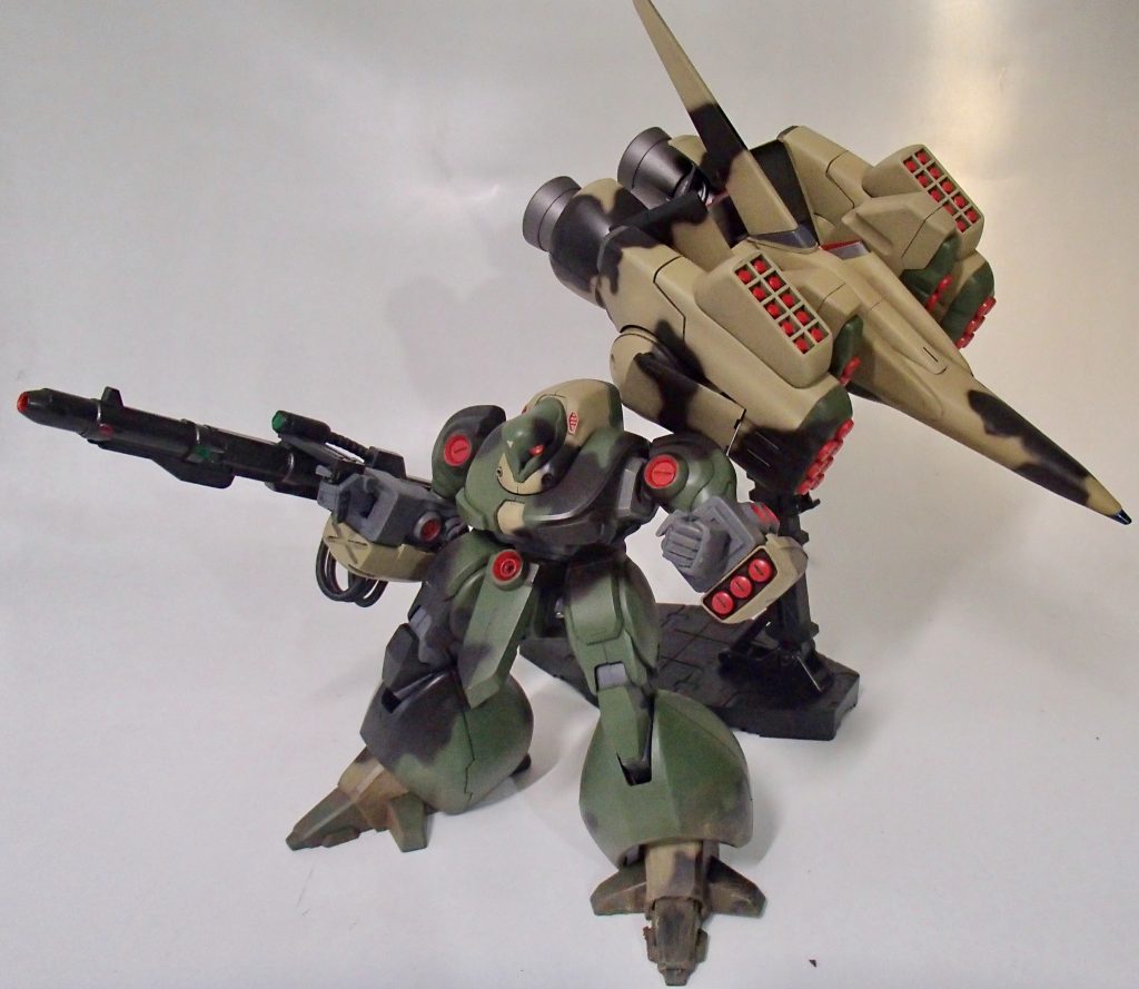 撹乱の為にブースターには大量のスモーク弾発射機が増設され、地表降下後の継戦能力向上を図る為、ガザDのナックルバスターに改修を施したビームランチャーを装備
ビームランチャーは取り回しとナックルバスター譲りの高出力、継戦能力を両立させる為、右腕のミサイルポッドを廃し代わりに大型のEパックを搭載し半携行式とした
配色は目立つ黄色から迷彩に変更、しかしスペースノイド出身のパターンは実用的な意味があまり込められていない
そんな設定です