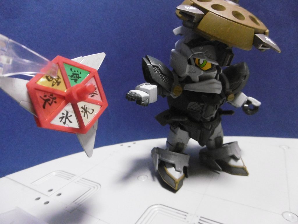 刃の刺さった場所に応じて特殊効果が発動します。文字盤をずらせばそれに応じた効果に。任意で刃を出したりしまったりもでき、投擲時に重力が掛かると自動で飛び出しもします。対物・対地・周囲とで効果が変わる設定。例えば自身の周囲に刃を突き刺せば、地面にその属性が付加される（ロマサガ３の「地相」のような類）といった感じに。刺さらなくても何かに当たれば効果が発動。

本来の効果と異なりますが、対物（対人・対機械含む）の例を挙げると、
炎：燃焼。追加ダメージ。放火（放火は忍術として実際に用いられている）
氷：凍結。関節部の一時的な麻痺。一定時間行動不能
雷：感電。センサー類の機能障害。電子ロックの強制開錠
光：閃光。センサー類の機能障害。陽動にも使える
爆：爆発。爆風範囲大・威力弱・相手に硬直時間発生。陽動にも使える
無：無属性。独楽使用時に限りなく消音（隠密時の道具として利用）

上記のような設定で、各々は基本的に逃走用の手段。「爆」以外は直接攻撃目的でまず使いませんが、陰術だけでなく陽術としても使用可能で、陽丸との共通装備の１つでもあります。
放下僧としては本体色が暗過ぎかもしれませんが、目立ち過ぎても良くなく、配色にかなり悩みました。