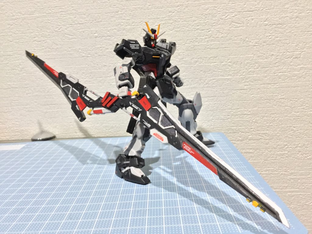 以下妄想設定
「我々が第七機甲師団と知ってもその刃を向けるつもりか!」
周りに取り囲まれながらもオッさんことキョウスケ・アイダは攻撃を緩めなかった。
  
クス。
「貴様!何が可笑しい。」
「あっあぁ〜ごめん。別に君たちを笑った訳じゃないんだ。」
キョウスケが操るガンダムノワールはバタフライバスターをソードモードに切り替えて応戦する。
「いつも周りに流されていた僕が必死になって足掻いているのが可笑しくて。」
 そう言いながらロンメル隊の一体を破壊した。
「貴様がやっている事はこの世界を崩壊させることに繋がるんだぞ!」
「だからって、あの子1人が犠牲なるのはありえない!あの子を助けたい。それがうちの隊長の願いだ。そして僕は隊長の意志を尊重したい‼️」
GBNに居場所を依存するユーザーは多い。中には身体的、精神的にGBNでしかコミュニケーションが取れない者もいる。キョウスケが所属するチーム 『ハロウィンジャック』の隊長のジャックもどちらかと言うとその部類に属すだろう。
近距離にいる部隊はあらかた片付けたが、その間に砲撃部隊に囲まれてしまっていた。
バタフライバスターのエネルギーは尽きビーム砲は撃てない。残るは実体剣のみ。バックパックを切り離し、ロンメル隊の射撃をかわしながら距離を取っていく。が、ロンメル隊に誘導され、周りを障害物に挟まれてしまった。身動きが取れず、正面からはロンメル隊が迫ってくる。
「貴様一人で我々第七機甲師団を相手によく戦ったと誉めてやろう。だがこれでチェックメイトだ。」
「ごめん。そうは行かないんだ。」
ストライクノワールが飛び上がると同時に切り離したバックアップから高エネルギーの光と衝撃が辺りを包み込んだ。
「相手がロンメル隊長率いる本隊じゃなくてよかった。。本隊だったら絶対にバレてるよ…」とキョウスケは思った。
「貴様…。これでタダで済むと思うなよ。」
「ああ。運営と有志連合を敵にまわしてるんだ覚悟しているよ…。」
「おいオッさん!そっちから高エネルギー波が検出されたが、そっちは大丈夫か!?」
隊長のジャックが心配して通信をしてきた。
「大丈夫ですよー。戦闘があったのかも知れないっすけど。ここには誰もいないっす。
残念ながら隊長が暴れる場面はないっすね。
自分は負傷したビルドダイバーズ側を見つけたら誘導するんで、補給物資までの退路の確保お願いしますねー。」
「おっおう。任しとけ。」
さて、この機体であと何体削れるか…。
直撃は免れたがバックパックの暴発はガンダムノワールにもダメージは加わっていた。全体に亀裂が入り右腕は損失していた。
軋む機体を動かしながらキョウスケはククっと笑った。
 今まで何かの為に必死で行動した事がなかった。そして誰かのために嘘をつくことも…。
ビルドダイバー側に加担したものは何らかのペナルティを運営から課される可能性がある。GBNが生活の一部となっている彼女はGBNに残るべきだとキョウスケは思った。だから彼女には戦闘に参加させないように配慮した彼の作戦だった。