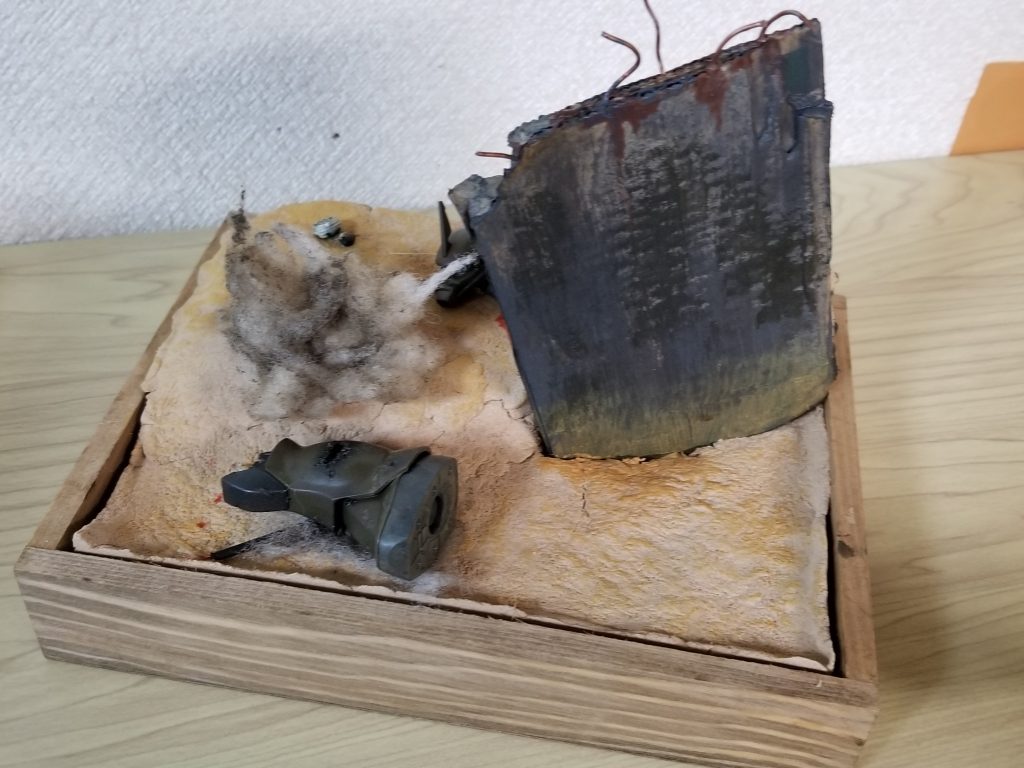 ジオラマ風ベース。100均のおがくず入り粘土を使っています。ほとんど塗装しなくてもそのまま地面の色に使えました。遮蔽物となるコロニーの残骸は段ボールを木工ボンドで固めて製作。ザクの残骸はジャンクパーツを加工して製作しています。