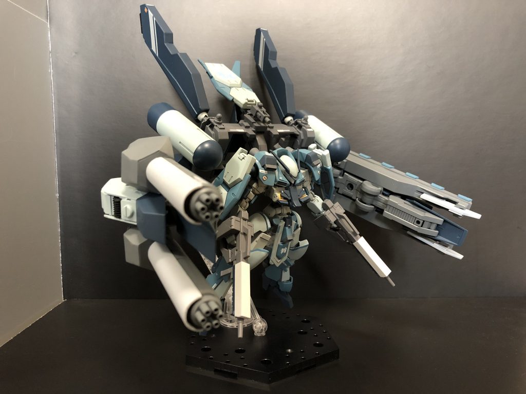 右アームには大型のガトリングを2門装備。銃弾はグレイズライフルと同口径のものを使用しているが、連射性はそれと比べ物にならず、継続して敵機を捉える事でナノラミネート装甲を徐々に蝕む。両アーム中央部には脚部増加装甲が推進器を保護する様に装着されている。
戦術としては、ミサイルによる弾幕を複数回展開し、周囲の敵機のナノラミネート装甲を削り、ガトリングで各個撃破する。