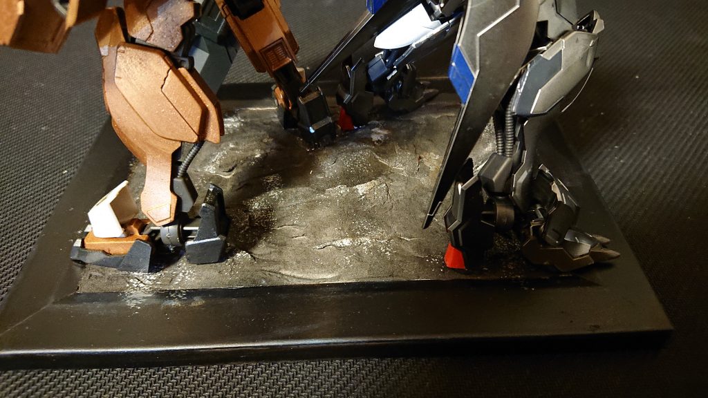 台座は、百均の額縁で石粉ねんどを地面にして、セミグロスブラックをふいて超荒い銀はげちょろを施しました。
鉄血らしく土っぽくしようとも思いましたが二機がそういうスタンスではなかったのでこのようにしました。