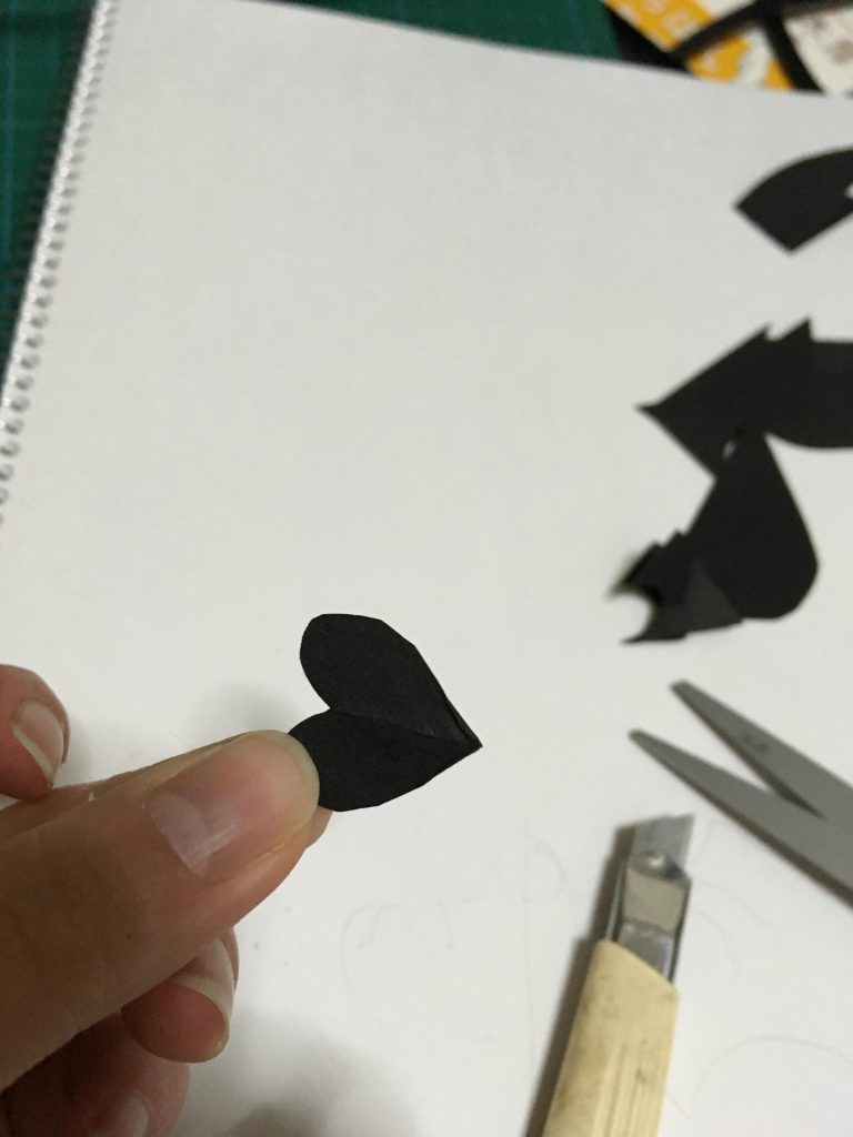 さて、翼を切った余りのところも半分に折ってちょきちょき…
こんなハート型を二枚作って、モールの片端を挟んで接着…