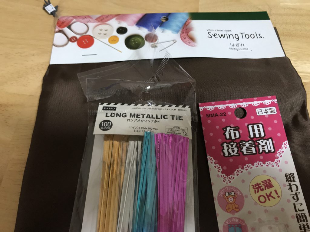 マントに使っている材料です。
全て100均で購入しました。
まず、はぎれを2つ折りにして使用するのを前提のサイズに切り、次に長さを調節したタイを2つ折りにしたはぎれの間に置いた後接着します。この時、接着剤がはみ出たりダメージ表現を行う事を考えて少し内側にタイを置いておきます。
乾いたらいい感じの見た目に仕上げて完成です。