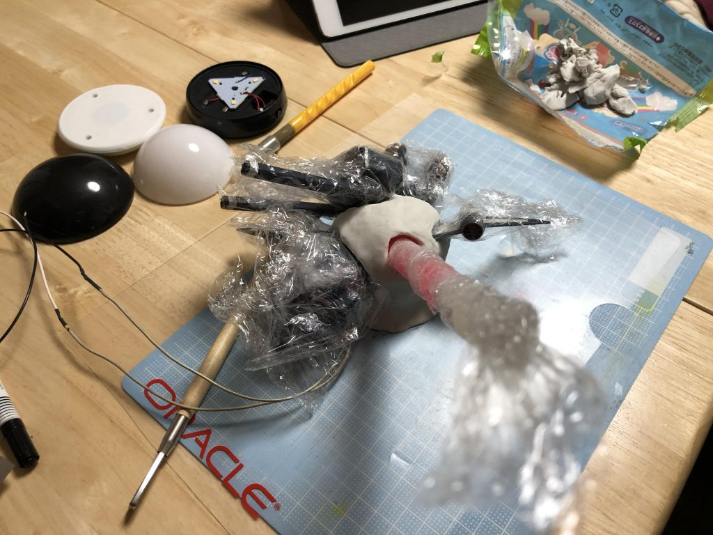 爆発エフェクトのオレンジの部分は、まず、油粘土で大きな球形を作り、そこにヘラなどで穴を開けて、分解したバクゥのパーツやサイリウムを挿して全体の配置を決めました。中に入っているLEDライトは乾電池式で平置きできる小型円形のものを選びました。(写真左上で分解されているもの)。