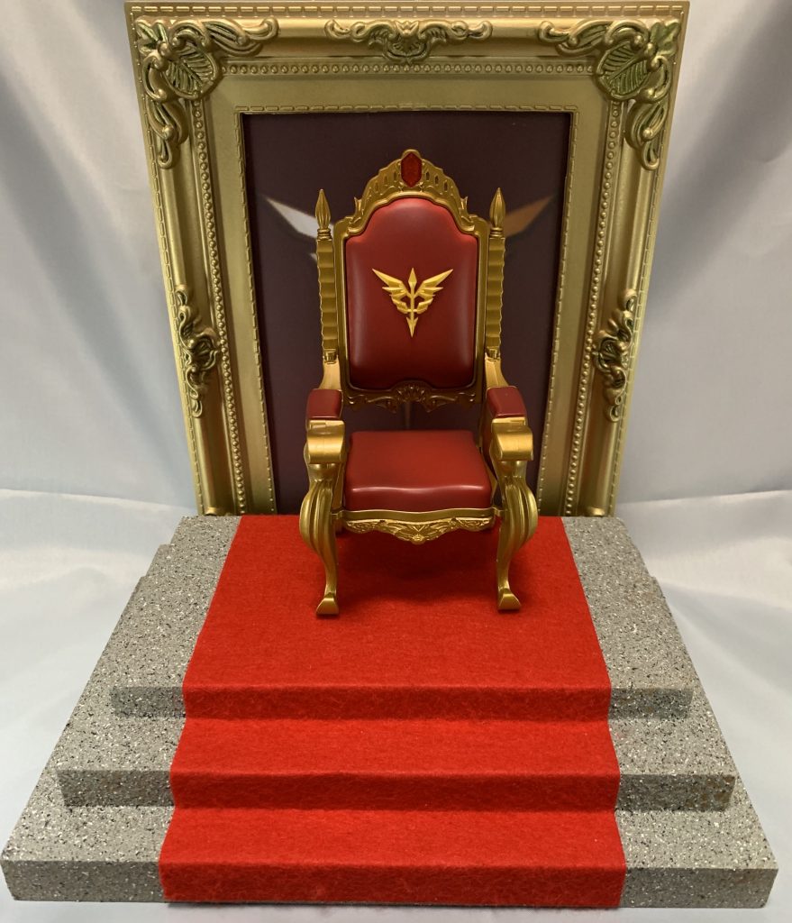 台座
木箱を重ねて、石調の塗装をし、赤いフェルトをカーペットに。
椅子は別のフィギュアのものを拝借しました。
後ろはアンティーク調のフォトフレームにネオジオンのシンボルを。