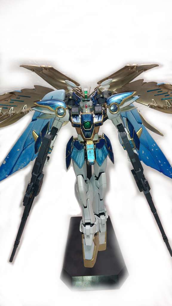 正面。ガンプラにゴールド使うの大好きマンです…。
しかし、何故こんな配色にしたのかというと。
このウイングガンダムゼロ(EW)を作るにあたって、先に設定を考えていました。
「もしEW後、ウイングガンダムゼロが大破せず残っていて、ヒイロがリリーナ専属の用心棒となっていたら…」
サンクキングダムの姫様で、ドーリアン外務次官ですよ。リリーナの側に居る者のMSですから、あのヒイロなら相応しいカラーリングにするだろうなぁ…という勝手な解釈から、人気のウイングガンダムゼロのカッコ良さ美しさを殺さず、それをグレードアップさせ、かつ設定に沿ったカラーということで、こうなりました^^;
故に、ウイングガンダムゼロ シュッツガイスト(XXXG-00W0/SG)という名前を付けて頂きました。シュッツガイストは、ドイツ語です。日本語で「守護者」を意味するそうです。