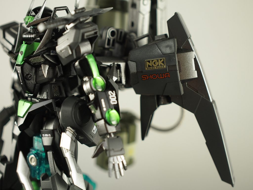 本来は黄色のアクセントになっているパーツを金属メッシュ折り曲げ加工した物(ヤットコやラジオペンチで製作)に置き換えています。
胴下~腰には小物接着でディテールアップを狙いつつ、腰の横はくりぬいてメッシュ窓を作り(やはり見辛いですが)追加した内部フレームイメージの金色に塗ったシリンダーが見えるようにしています。
肩には横の隙間にダクトを追加し、左肩にはナイフを収める鞘を真鍮線で追加。
腕には本来GNソードの固定パーツを刺す穴にメタリックテープとメッシュで蓋をし、肘にMSGの刃物一杯入ってるヤツに付属してるクナイを追加。
射出できる隠し武器だったり、しなかったり。
腰にはEz-SRのブースター追加。写真では完全に死角ですが、排気口にメッシュかぶせてます。
また、トゲトゲした雰囲気を出すためにMSクローを真鍮線で追加。膝にもクローを追加し、膝蹴りしたら痛そうな雰囲気に。
脚部にはMSグラントのホバーユニットをMSGメカニカルアームで接続。膝横のクリアパーツは腕のクリアパーツ部分と同様の処理。
良い感じに光ってると思います。