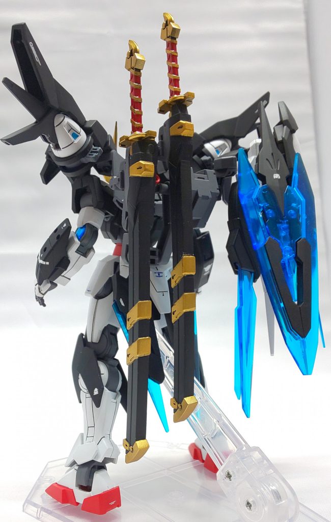 背面左側に装備された2振りの剣、『刹那』と『ローダンセ』。
通称【グラハムソード】
対Eカーボン・GNフィールド切断力に特化した実体剣で、表面に僅かなGN粒子をまとわせることで、対弾・対GN粒子防御装備としての機能もあります。
向かって左側(外側)に懸架された方が『刹那』で、右側(内側)が『ローダンセ』になります。
これは、自分をガンダムマイスターに導いた刹那・F・セイエイへの変わらぬ友情・想いを込めてグラハム自らが命名しました。
この二本の剣は、Eカーボンの装甲を紙切れの如く切断し、ネオ・ジンクスやソルブレイドの纏うGNフィールドすらも易々と切り裂くほど研ぎ澄まされた刀なのです。