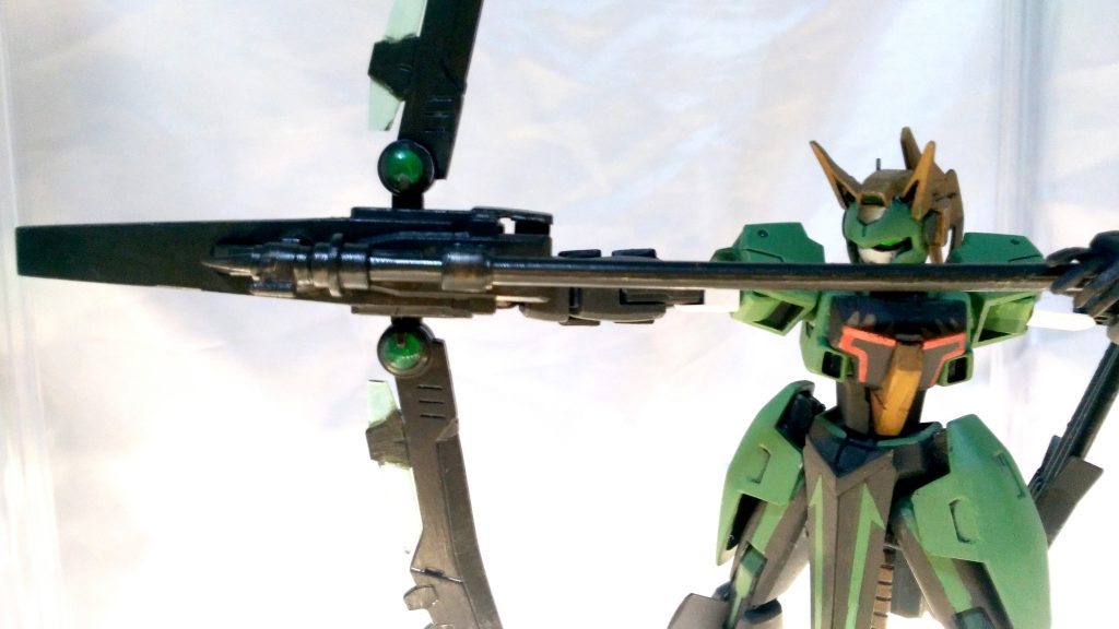 ・GNコンパウンド・ボウ「タウロポロス」
右腕にビルトインされる大型の弓型複合射撃武器。GNビームガンに加え、ダインスレイヴのような特殊な重徹甲弾を射出する事も可能。
予備実体弾は背部に接続されたサボットに装着される。武装に設けられた小型GNコンデンサーから射撃用粒子を出力するため安定した高威力射撃が望める。