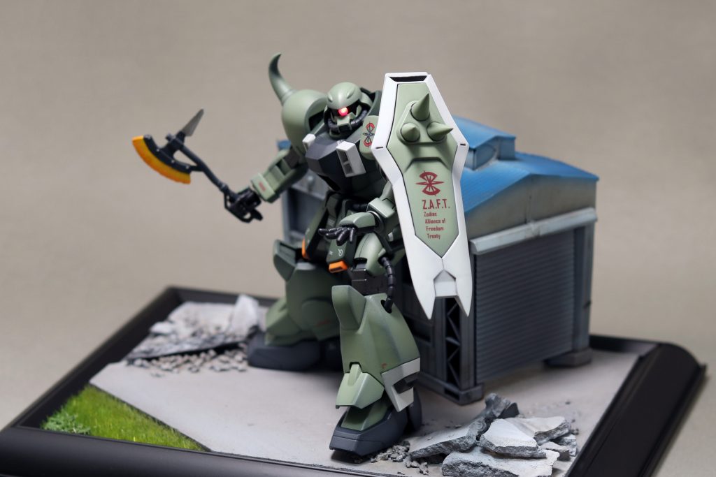 台座はアーモリーワンのモビルスーツ工場をイメージして制作しました。ほぼ100均の素材で出来ています。地面はMDFとダンボール、瓦礫は石膏とコルク、建物は鉄道のおもちゃ。草はグリーンシート、外枠はフォトフレームを使っています。1000円以内で作れる安さが魅力です。