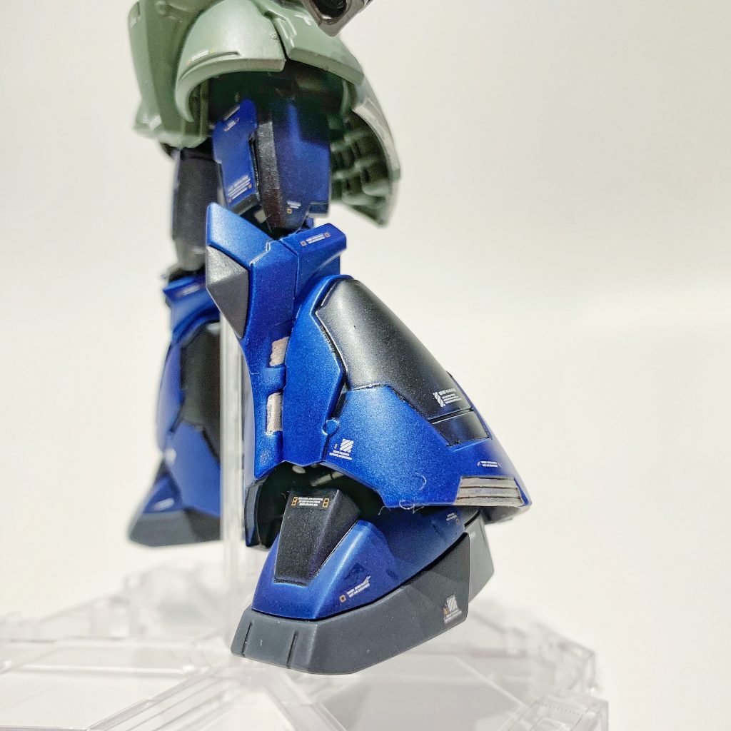 ガトー専用ザクと同じく、塗装はタミヤスプレーのマイカブルーとダークマイカブルーを使用して別パーツ感を表現。内側(ダークマイカブルー)の上に外側(マイカブルー)の装甲が被さっているイメージで。【製作工程】①ゲート跡とパーティングラインを処理して、パーツ洗浄。②頭部アンテナを先鋭化。前頭部ひさしを切削して、モノアイ視認性アップ。③タミヤ メイクアップ材シリーズ No.64 ファインサーフェイサー L (ライトグレイ) で下地塗装。④ラッカースプレー(タミヤスプレー TS-50 マイカブルー、TS-64 ダークマイカブルー、TS-78 フィールドグレイ)とエナメル塗料により全塗装。⑤ガンダムデカールNo.116 RG 1/144 MS-06R汎用1、ガンダムデカールNo.114 HG 1/144 機動戦士ガンダム サンダーボルト汎用1、ハイキューパーツ 1/144 RB01 コーションデカール ホワイト&オレンジを使用してマーキング。⑥GSIクレオス Mr.トップコート 水性プレミアムトップコート 半光沢 スプレーで仕上げ。⑦モノアイとビームライフルのスコープに、ダイソーのスワロフスキー社製クリスタルストーン(ライトローズ)を使用。