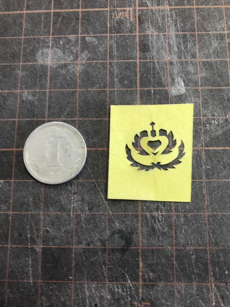 アインフェリアのユニットロゴは、マスキングシートの台紙に印刷したものを切り抜きました

  台紙から黄色いマスキングを一旦剥がしてその台紙に印刷をして貼り直し、印刷された台紙側から切り抜き
  
  ご覧の通り大きさは一円玉くらいですが、左右対称なので中央で折り畳んで切り抜いたためあまり手間はかかりませんでした