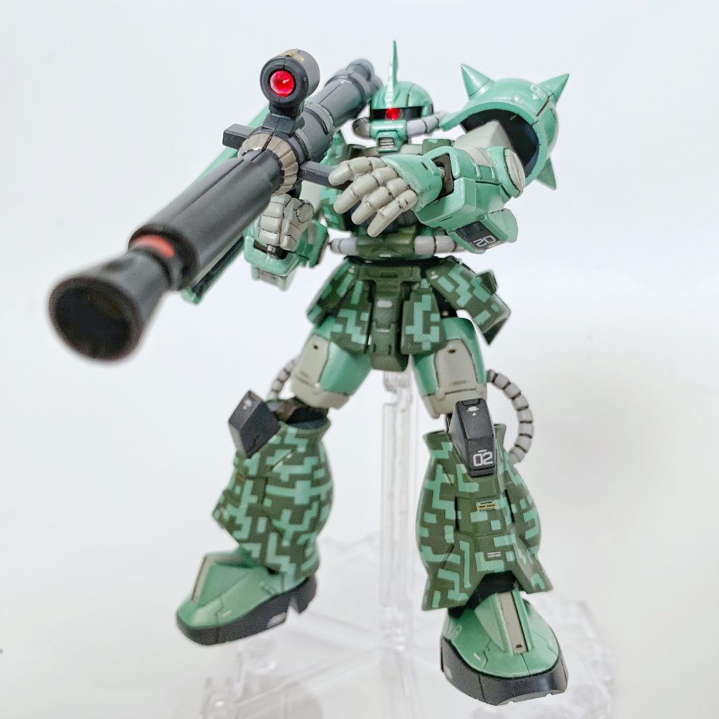 塗装したハイパーバズーカを持たせて、軽くポージング3【製作工程】①ゲート跡とパーティングラインを処理して、パーツ洗浄。②頭部アンテナ、左肩アーマーのスパイクをシャープ化。③タミヤ メイクアップ材シリーズ No.64 ファインサーフェイサー L (ライトグレイ) で下地塗装。④ラッカースプレー(タミヤ スプレー No.60 TS-60 パールグリーン)で塗装。⑤ハイキューパーツ ドット迷彩用マスキングテープ S(DCMTS)で都市型迷彩(ドット迷彩)の塗装下地作り。⑤ラッカースプレー(タミヤ スプレー No.78 TS-78 フィールドグレイ、No.48 TS-48 ガンシップグレイ、GSIクレオス Mr.カラー スプレー S11 ガルグレー、S78 メタルブラック)とエナメル塗料により全塗装。⑤コピックモデラー0.02のブラックでスミ入れ(一部ウォームグレーも使用)。⑥ガンダムデカールNo.116 RG 1/144 MS-06R汎用1、ガンダムデカールNo.114 HG 1/144 機動戦士ガンダム サンダーボルト汎用1、ハイキューパーツ 1/144 RB01コーションデカール グレー&オレンジを使用してマーキング。⑩GSIクレオス Mr.トップコート 水性プレミアムトップコート つや消し スプレーで仕上げ。⑪モノアイとバズーカのスコープに、ダイソーのスワロフスキー社製クリスタルストーン(ライトシャム)を設置。