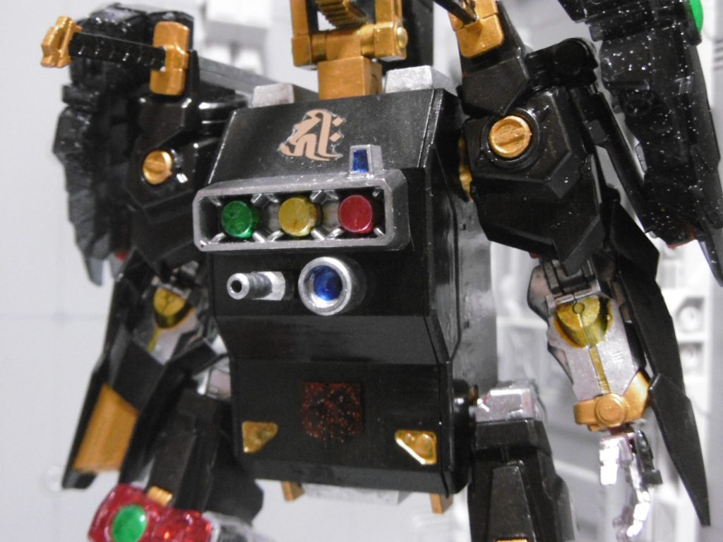 正面には三連ミサイルポッド・機銃・ビーム砲を装備。下部に装甲版（戦国ＰＰＣの分解時に出た破損パーツ。背面にもあり）
ミサイルはスタークジェガンのを接着、他はＨＧＢＣジャイアントガトリングのＢＪ受けとセンサー。両肩中央はディテールを落とし、ＭＳＧマイナスモールドⅡを接着。
ミサイルポッドはたまたま信号機にも見えたので、それっぽく塗りました。スターブライトシルバーを下地に水性クリアー各種を筆塗り。冗談みたいな外見でも威力は変わらない。
ミサイル下のを青いセンサーだと勝手に思い込むと、ビームが飛んできます

目にあたる箇所はポッド左角の小さなセンサー。丹下左膳は「右目と右腕が無い」ので、それに沿った表現。ノーネイムの前腕を使ったのもそのため（細かい所は違っていても概ね同じ）。戦国肩＋ノーネイム前腕の組み合わせは、肘の干渉により可動域が更に狭まります。しかしこの機体はガシガシ動くものでもないので調整なし

隻手＋サブアームの構成から、梵字【千手観音菩薩】デカールを使用。
忍者ではないため深い設定はありません。ただし「延命・滅罪・除病の功徳」から転じて『絶対服従の呪印』としての意味を付加。主君に支配される関係にあります。もしかしたら動力源は呪いなのかもしれない