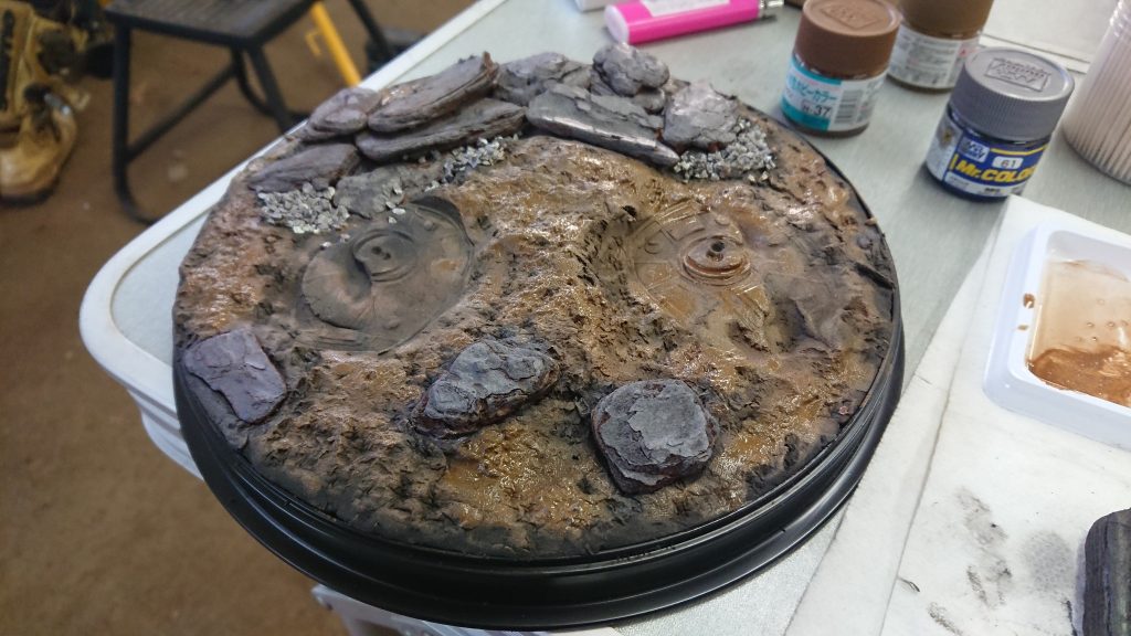 紙粘土が乾いてから地面をダークアース、ウッドブラウン、ウェザリングカラーのグランドブラウンで塗りました。下地の紙粘土が黒だと適当に塗っても色に表情が出て良いですね。
岩はグレーに塗りましたがちょっと不自然に感じたのでこの後からグランドブラウンを塗ったら色味が暗くなりすぎてしまいましたのでこのままでも良かったかもです。