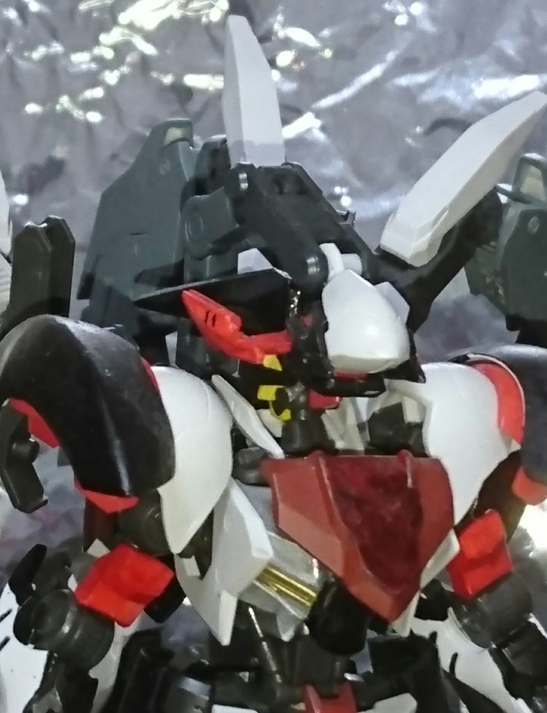 鉄血二期の後にラスタルの指導の元建造されたガンダムフレームの一機。顔を被っている物はリミッターの役割を補っており、通常戦力相手ではこの姿で戦闘を行う。この状態の本機は傲慢<プライド>の名で呼ばれている。