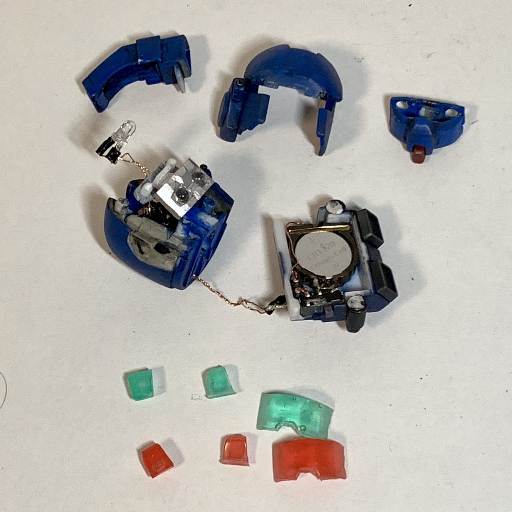 頭部に砲弾型LEDを3球と定電流ダイオードを搭載、パックパックに電池ケース(CR1220)とスライドスイッチ、頭部配線との接続用ソケットを搭載しています。パックパックの外装はネオジム磁石で固定していて、簡単に開閉できるようになっています。塗装完了後に外していた回路一式を戻して点灯してみたら、メインカメラのLEDが点かなくなってて涙目でLEDを交換しました。(多分、パーツへの付け外しの際にLEDの端子を引っ張ってしまったのが原因)ちょっとLEDが明る過ぎたのが反省点。肉眼ならそうでもないんだけど、写真に撮ると明るすぎでした。ハンドパーツ