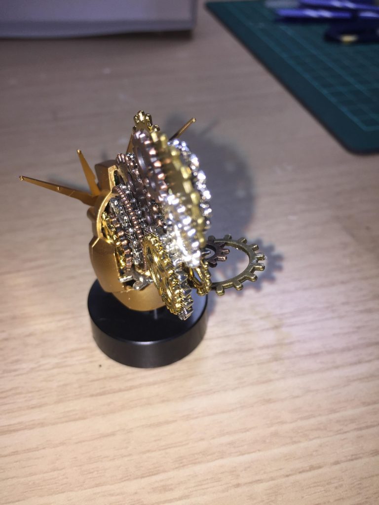 金色はレッドゴールド単色です。νガンダムの生首の後頭部をばっさりと切り落として、その中に歯車を仕込んで、接着していくことで作成してます。