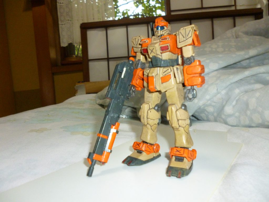 正面素立ちです。
今回のベースキットとなったジム・ストライカーは設定上、このデザート・ジムを発展させた「装甲強化型ジム」の近接格闘仕様ということらしいので、大まかな形はそこまでいじらずに済みました。
しかし、各部スラスターや追加装甲など、削ったり付け足したりしなければならなかった部分も多く、プラ板やエポキシパテで形状変更していきました。
正面の主な変更点は
・胸部ダクトの上に追加された小さなダクトをプラ板とパテで製作
・フロントアーマーの装甲を一部削り取り、デザート・ジムの設定画に合わせたものに置き換え
・前腕部のアーマーを削り取り、エポキシパテで装甲を新造
・膝アーマーの突起(スパイク?)を削り取り、パテで設定画に合わせた形に変更
・アンクルガードにプラ板で追加装甲を取り付け
・つま先にそれぞれ2つずつ、スパイク(滑り止め?)のようなものをプラ板で追加
こんなところでしょうか?
あ、それから、口に当たる部分の装甲にカッターでバツ印に彫刻を追加しました。
ちなみにこの機体、この口(?)のために、一部では「ウサギジム」なんて呼ばれているとかいないとか・・・。