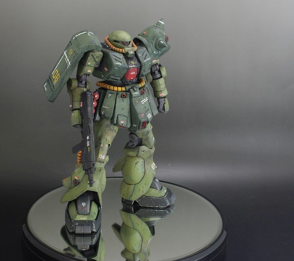 ▼チッピング（ダークグリーン部・ライトグリーン部）
　チッピングはメカサフの上にシリコンバリアを塗布してから、
　上塗りして、実際にナイフで上塗り層の塗膜を剥がしています。
　

１）メカサフヘヴィを更にトーンを落としたもので下地塗装
２）クレオスのシリコンバリアをエアブラシをパーツに塗布
２）基本色をエアブラシ塗装
３）ハイライト色を吹いて、軽くグラデーションをかける
４）平筆に適度に薄めた赤いエナメル塗料を含ませて、
　スパッタリングの要領で、チッピングの位置と大きさを決めるため、
　飛沫を飛ばす。
５）付着した赤い塗料のついた場所をデザインナイフでカリカリ削って
　チッピング。傷の大きさも、塗料の付着した点の大きさと角度で
　適度に調整する。
６）カリカリチッピング終わったら、残っている赤い塗料を拭き取る。
７）その上で、エッジをメインにに手動で傷をつけていく。この時はデザインナイフだけでなく、いつも使わずじゃまだった120番の神ヤスでも傷をつけました。シールドの等のエッジの部分は神ヤスの方いいかんじですね。

という感じでやりましたー。大げさに書いてありますが、作業自体は単純で手間もたいしてかからずサクサクでしたー。

わざわざスパッタリングで傷の位置を決めたのは、
完全に主観でチッピングの傷をつけると、どうしてもわざとらしく不自然な偏り方をしたチッピングになってしまうからで、物理法則の力を借りて、自然なランダムな傷の位置を決めてみた感じです。基本、スペースデブリによる傷は斜め上前方からつきますので、そちらからのスパッタリングを多くし、この辺で機体のそばで爆発があったことにしよう。って場所からまた改めてスパッタリングしたりしてます。
自然な傷をつけてから、さらに人間の手によるわざとらしいけどドラマチックな傷を主動でつける。そんな感じです。