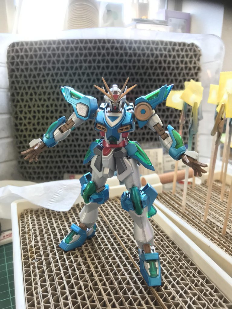 サーフェイサー1500で下地、
内部フレームはウッドブラウン
外装は一度シルバーで塗装のあと、白がGXホワイトシルバー
青はメタリックブルー、赤はメタリックレッド
黄色はミスターメタリックカラーのゴールド
黒はセミグロスブラックがベースになってます。ちょっと調色いじったのですが、感覚すぎて覚えてないのです。
おめでたい感じにしたかったので、メタリック中心に艶っぽく。
要所要所につや消しの配色で落ち着かせる雰囲気にしています。
クリアーパーツはラメクリアーレジンで複製しようと頑張りましたが、精度が低すぎて挫折。
そもそもクリアーイエロー吹いたら普通にいいグリーンになりました。
クリアーパーツが付くところはシルバーが残るようにマスキングで守っておきました。
塗装後のスミ入れで、
フェイスなどはタミヤのいつもの。
ボディはゴールド、
技っぽい手のひらはメタリックレッドです。