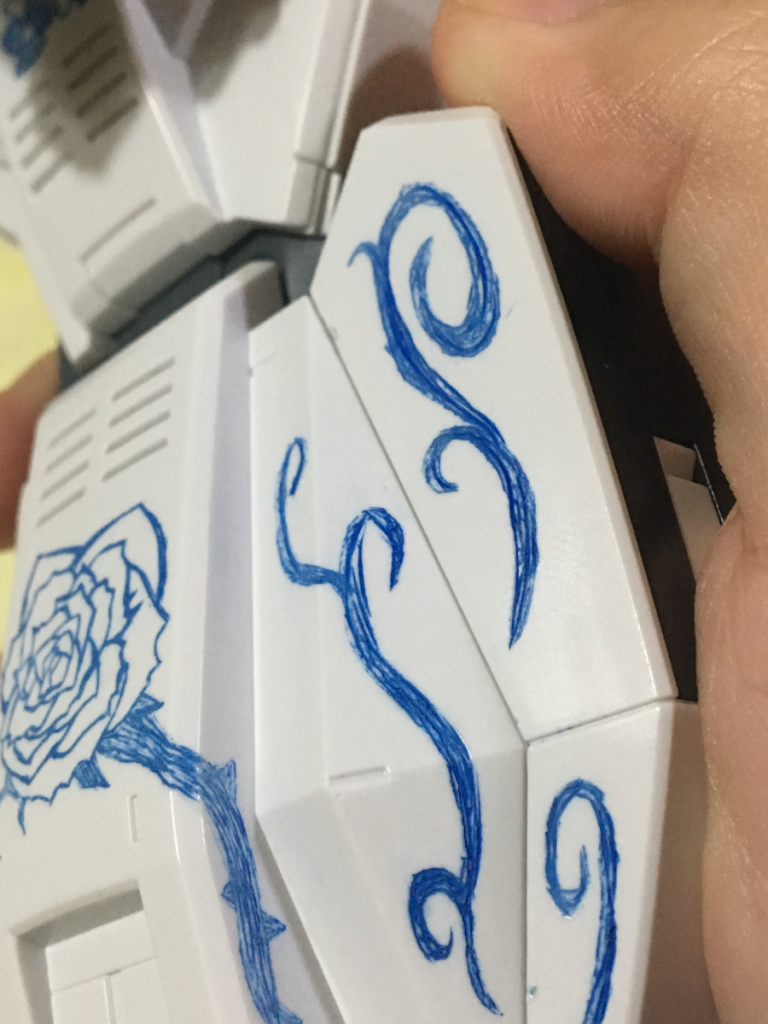 右脚スネ部分を拡大しています。
こちら、デカールなどを一切使用せず、三角刀とケガキ針でプラスチック表面を直接削って模様を描き、彫った箇所にガンダムマーカーで色を落とし込んでいます。触ってもらうのが一番わかりやすいのですが……