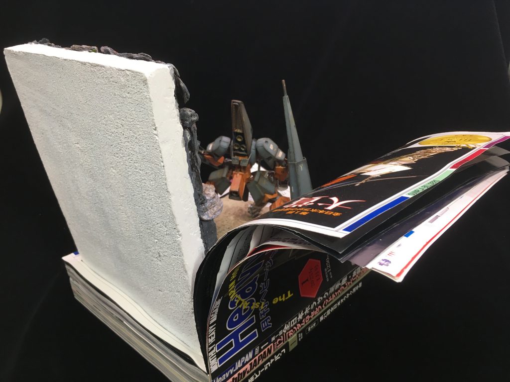 見開いた状態を作成する為、ジオラマ台座の自重を重しにアルミ板が開いたページを曲面状に保持しています。