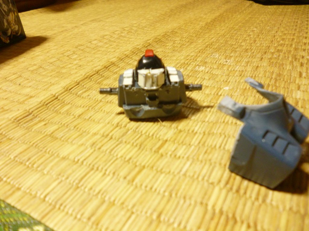 頭部の加工です。
個人的にドワッジを作る上で一番難しいポイントの一つが、この頭部の形状の解釈だと思っています。
設定画はもちろん、ＭＧのキットや多くの方の作例でも、後頭部をグッと伸ばして、そこに後方用カメラがある、という形になっているものが多いのですが、あの後頭部がニューッと伸びた感じが、なんだかエイリアンみたいでどうしても好きになれなかったため「後方用カメラは頭部に直接付いているのではなく、後頭部を保護する装甲板の表面に設置されている」というオリジナル解釈で製作することにしました。
というワケで、まずは後頭部を延長する基部となる部分をプラ板で作っていきます。