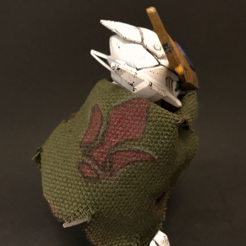 マントは百均のポーチを切ってつくりました。実際に火で炙っているので、ウェザリングでは出にくい雰囲気が!
後ろには鉄華団のマークがありますが、本人はどんなものか覚えていない様子。ただ、「大事な誓いを立て、背負わなくてはならない気がするから」という理由でマントにこのマークをつけています。