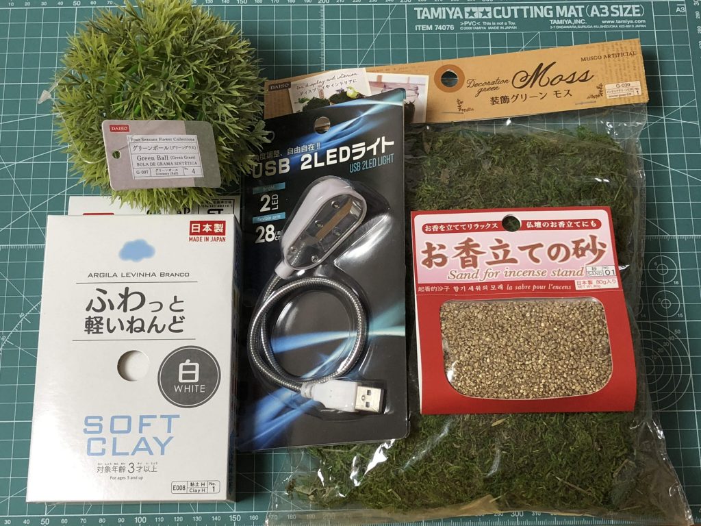 ダイソーで集めた素材。グリーンボールを木の幹に、ふわっと軽いねんどを地面に、2LEDライトをモノアイ発光に使用しました。今回は使いませんでしたが、お香立ての砂が岩素材として使えそう。