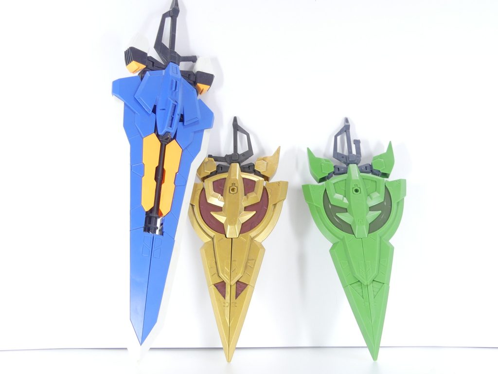 量産型ジオニックソード：ジオニックソード（EX19参照）の「量産型」ともいえる超大型実体剣。これはＧＢＮがデータとして作ったものでもなくアルザスが実際にテストしたわけでもない、ビルダー一人一人が「ビルド」した武装である。そのため、形状以外の性能・形態変化は全て一個一個異なるのである。キャプテン・ジオンのフォロワーがオリジナル・ジオニックソードの勇姿を目に焼き付け、量産された本武装を大挙して作成していく光景を、キャプテン・ジオン本人は「キャプテン・ショック」と呼び称えた。今回はシール無しの素組みです。貼る部分は濃い緑部分、この写真でなんとなくわかるでしょうか。一番左は旧キット1/100のタクティカル・アームズ（一部パーツ無し）。刀身部分などは異なりますが、基本ギミックはこちらを流用したもの。柄の部分は形状・ギミック共に全く同じです。ジオニックでは３ミリ軸で取り外し可能。元のタクティカル・アームズには柄の部分が90度折れ曲がってスラスターになる機能がありましたが本ソードではオミット。