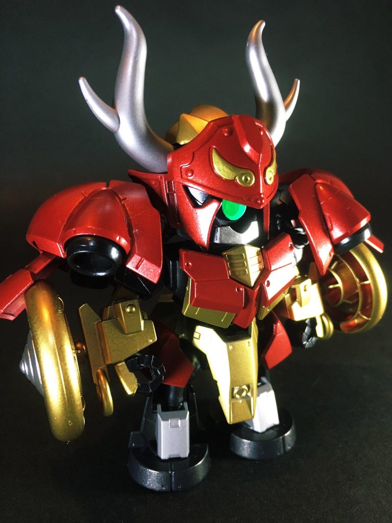 モチーフを田単とするにあたって、以下の2点は外せないポイントと思いデザインに反映しました。
①火牛の計
大量の牛の尻尾に松明の火を燃やして、角に刀剣を括り付け敵陣に暴突させた計略。後ろに精兵が続き、事前の調略も全てが功を奏して慢心していた燕軍を徹底的に潰走せしめた。この戦勝を契機に斉軍の反撃が始まり、奪われていた七十余の城を僅か数ヶ月で全て取り戻した(司馬遷『史記』)。
本邦でも源平合戦時、倶利伽羅峠の戦いで木曾冠者源義仲が用いたという逸話が有名です。
②車輪の補強
合従軍襲来の折、事前に情報を察知して緊急時に長距離移動の必要があると予見した田単は、馬車が荒野を高速で走れるよう車輪の軸を堅固に補強していた。
果たして予見通り敵襲を受け、緊急脱出した人々には途上馬車の軸が折れて逃げ遅れ捕虜となる者が多くあったが、田単の一門だけは無事に撤退する事が出来た。
この先見の明が評価され、田単は市場の下級役人から一軍の将へと抜擢される(司馬遷『史記』)。
牛角は鬼牙装関羽ガンダムの兜から拝借しました。
頭部はHGヘルムヴィーゲの頭部パーツでは小さくて使用出来る部分が無かったため、三国伝の呂蒙ディジェ、甘寧ケンプファー、呂布トールギスや黄蓋グフから組み合わせてそれっぽく造型しています。
腕部の車輪はビルドファイターズトライのSD紅武者アメイジングから流用しました。
手甲に向けて伸びる輪っかの部分も、牛の鼻輪っぽい形状でイメージに合いちょうど良かったです。
ヴァルキュリアバスターソードはHGサイズのままではあまりに巨大だったので、刃を大幅にカットした上で接合し短くしました(それでもかなり大きいです)。
田単にとって最大最強の宿敵は楽毅であり、この二者をオリジナル武将化するにあたって演者をライバル関係にしたいという思いも若干ありましたが、一方で楽毅は燕国の内政事情から既に失脚・亡命しており、直接的には田単と干戈を交えたわけでない、という点から関係性よりも各々のキャラ設定に合う演者を優先しました。
対戦艦級用のヴァルキュリア破砕大剣はそんな楽毅ゼネラル・レビルへの対策として導入しつつも、実際に使われる事は無かったという設定です。