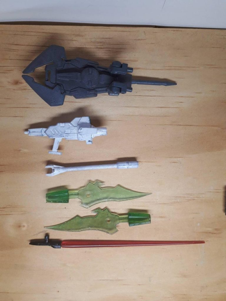 *3. 兵装解説1(外装・本体部)
 3-1 準万能兵装スヴァイル(複合型GNシールド)*
  カスタマイズキャンペーンのものに0ガンダムのGN粒子発生器とバトルアームズのジョイントを取り付けた。シールド・GNフィールド発生器・スパイク・ク
ロー・ジョイント部の小型射撃装置・分解してアックスと多種多様な機能を持つ。
*3-2 万能兵装ミステルタイン(白の複合兵装)*
  出撃時にはロングライフルとして使用される。バレル部分をはずせば短砲身
のライフルとしても機能しバレル部分はビーム薙刀としても使用できる。なお
砲身のみで殴っても一応ダメ―ジは出る。
*3-3 万能兵装ルーラレア改三式*
  ルーラレアにかわり正式採用された。ビット機能が強化され、コンデンサーも大型化した。コンデンサーにはスラスターの噴射口が付けられ、ビットして動いているときでも射撃が可能になった。このほかにルーラレアとあまり仕様の変わらない量産しようRe-ルーラレアが存在する。
*3-4 着脱式GNビームサーベル*
  腕部に直接装備、エネルギー供給ができるビームサーベル。