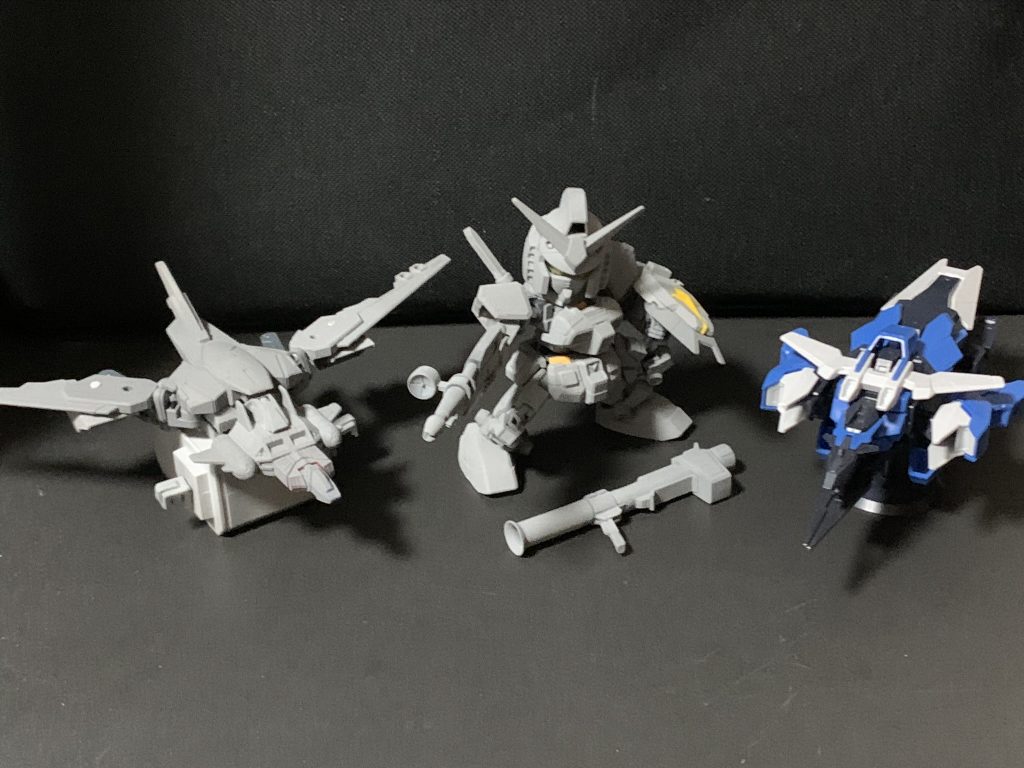 サフ状態今回の塗装は以下の通り。特に記載のないものはアクリジョン 。基本塗装下地: アクリジョン ベースカラーのホワイト+グレー (3:1ぐらい)白: ベースホワイト赤: ベースレッド→モンザレッド黄色: ベースイエロー→黄色+オレンジイエロー (1:1)青: ベースブルー→青+紫少量ダークグレー(コアガンダム): 以前、バンシィを塗装した時のあまりダークグレー(SDガンダム): ジャーマングレーライトグレー(支援機): 明灰白色(が足りなかったので白とグレーを足して大体同じぐらいの明るさに)シルバー: 水性ホビーカラーのシルバーガンダム頭部のカメラ: 蛍光レッドその他、一部ガンダムマーカーも使用。ウェザリング等パーツ着脱の塗装剥げや色移りを考慮して汚し気味にしています。白パーツを一旦水性ホビーカラーのクリアをかけてから、ウェザリングカラーのマルチグレー、その他をマルチブラックでスミ入れ。エッジをアクリジョンのシルバー、一部焼鉄色でドライブラシ。仕上げ水性ホビーカラーのつや消しクリアでトップコートして完成アースアーマーは成型色にスミ入れ、ドライブラシ、つや消しコートのみです。アクリジョンのつや消しはガサガサ感が強すぎたのですが、水性ホビーカラーのつや消しはかなりいい感じです。アクリジョンよりは溶剤臭がしますが許容範囲です!身長比較