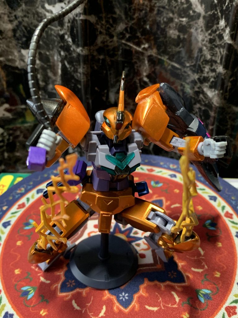 護衛用の機体であり、高火力の武装は装備していないものの…
メタルウィップ、ビーム・ストリングス(発射口は膝裏に変更)に加えて腰部にトリモチランチャー発射機を追加し、
敵機を捕縛ないし妨害する戦法に長けたコンセプトはしっかり継承されている。