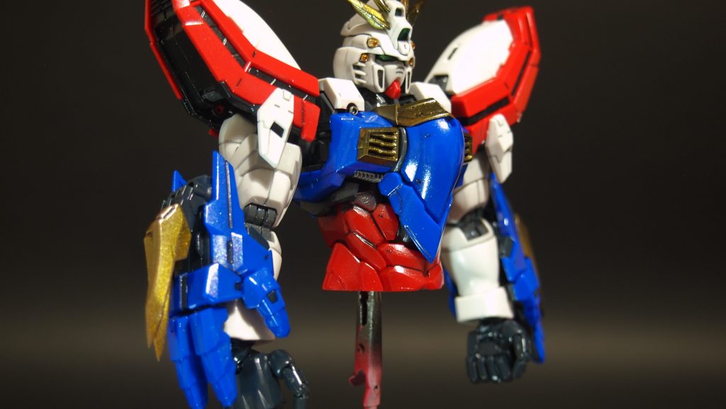 顔まで筋肉質で胴長な印象なので、フェイスパーツや目のまわり、カメラアイ周辺をけずりこんでエッジをだし、シャドーを吹いて膨張色の顔を締めました。肩や顔のガトリングをメタルパーツにし、アンテナやクロー、ダクトの黄色パーツは重みを感じさせるスターブライトアイアンにクリアーイエローをふきました。脇腹付近もけずりこんでシャープにし、青の胸パーツと赤の脇腹パーツの境目にフィンモールドをいれ、グレー塗装部分をつくることで胴長な印象をおさえました。