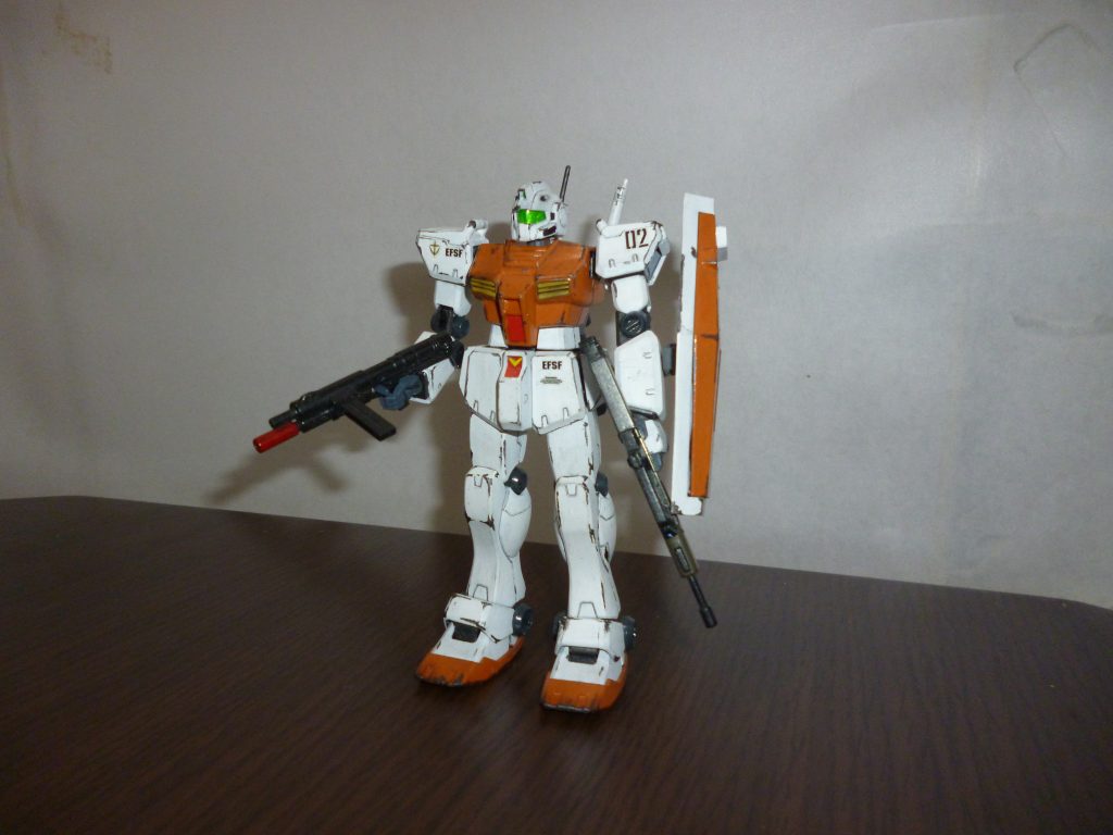 正面素立ちです。
今回使用したのは「HGUC ジム改」です。
左手でも銃器類を構えられるよう手首を「HGUCジム・クゥエル」から流用した以外は、本体にはこれといった改造は加えていませんが、塗装はそれなりにこだわりました。
基本カラーはツヤ消し白に、オレンジとミドルストーンを混ぜたくすんだオレンジ色です。
この作品を製作中に、模型仲間の友人に「赤系の色で寒冷地仕様っぽい色って何が良いかな?」と相談したところ、「オレンジっぽい色が良いんじゃね?」とアドバイスをもらったので、それをそのまま採用しました(笑)。
基本塗装が終わった後、全身に黒鉄色でウェザリングを施しました。
ちなみに、スミ入れはシャープペンです。