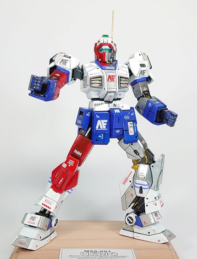 ●「軍用機にメーカーロゴって、うーん」派なので普段はアナハイムエレクトロニクスのロゴは貼らないのですが、今回はメーカー内でのテスト機ということで貼りまくってみました。

●また、テスト機設定ということで、トリコロールカラーということとも合わせて今回は（筆塗りのくせに）グロス仕上げを試してみました。軍用機仕様の塗装をしていない設定です。

●突飛な色、形であるほど、コーションデカール多めでリアル感を足した方が良いのでは？と考え大量にデカールを貼りましたが、スポンサーロゴが大量に貼ってあるＦ１カーみたいになってしまいました。まあコンセプトカー感が出てよかったと思います。

●あと、各スラスターはMGの肩を参考にすべて下辺をオープンな感じにしてみました。